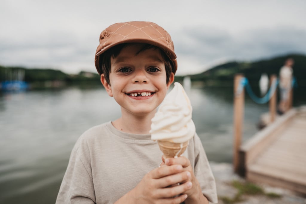 Ein Junge mit Zahnlücke hält ein Eis in den Händen.